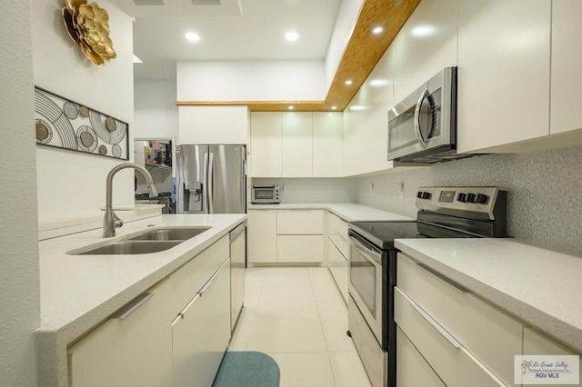 kitchen with decorative backsplash, light tile patterned flooring, sink, and stainless steel appliances