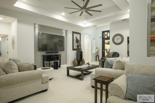 living room with a raised ceiling and ceiling fan