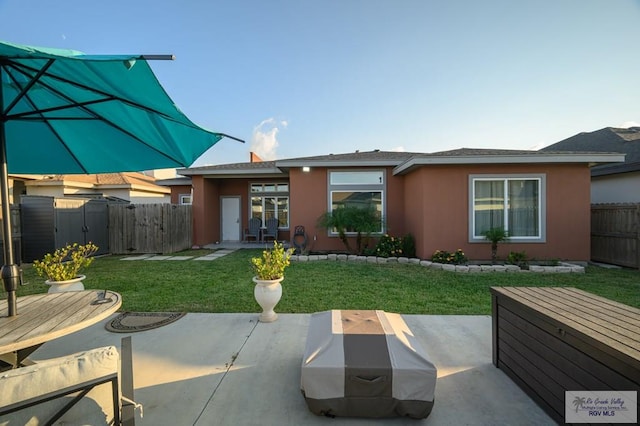 back of house with a lawn and a patio