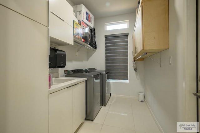 clothes washing area featuring cabinets, sink, light tile patterned floors, and washer and dryer