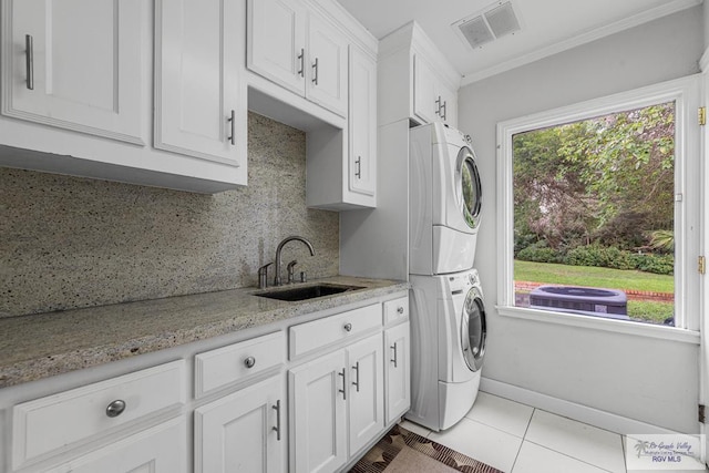 2301 Riverside Dr, Harlingen, TX 78550 - laundry room with light tile patterned floors, visible vents, cabinet space, stacked washer / dryer, and a sink
