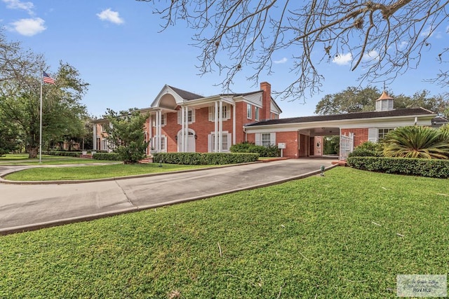 2301 Riverside Dr, Harlingen, TX 78550 - neoclassical home with an attached carport, brick siding, driveway, and a front lawn
