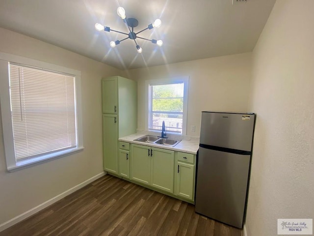 kitchen with dark wood-style floors, a sink, freestanding refrigerator, a notable chandelier, and green cabinets