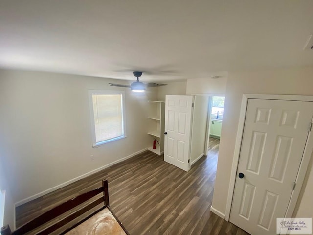 unfurnished room featuring baseboards, dark wood-style floors, and ceiling fan
