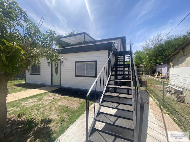 view of side of home featuring stairs and fence