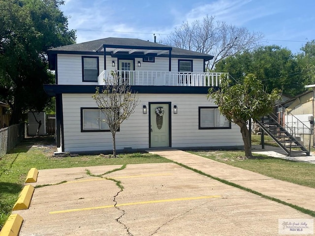 view of front of property featuring fence, stairs, and a balcony