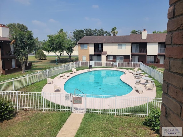 view of pool with a patio and a lawn