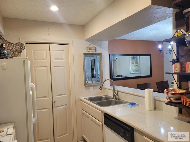 kitchen featuring white cabinets, white appliances, sink, and a textured ceiling