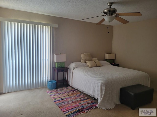 carpeted bedroom featuring ceiling fan and a textured ceiling