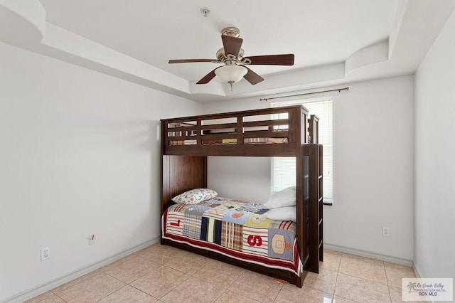 bedroom featuring ceiling fan, light tile patterned flooring, and a raised ceiling