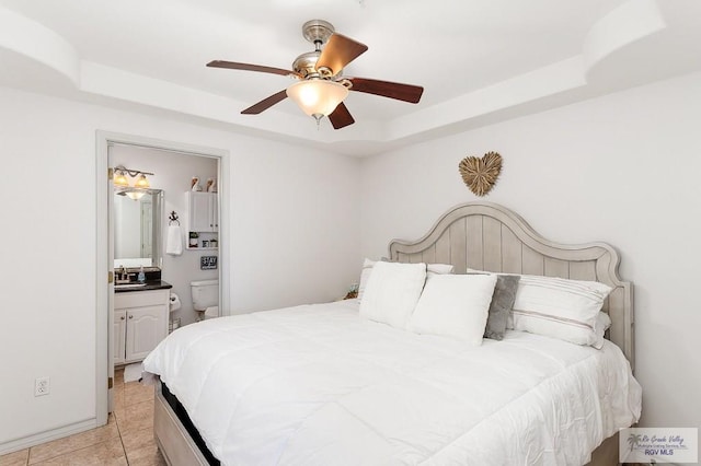 bedroom with a tray ceiling, connected bathroom, ceiling fan, and light tile patterned floors