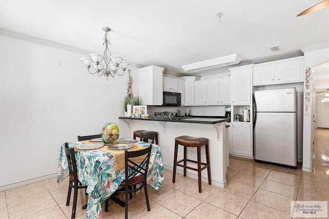 kitchen with a breakfast bar area, kitchen peninsula, white cabinetry, and refrigerator