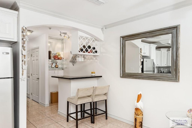 bar with crown molding, white refrigerator, white cabinets, stainless steel refrigerator, and light tile patterned flooring