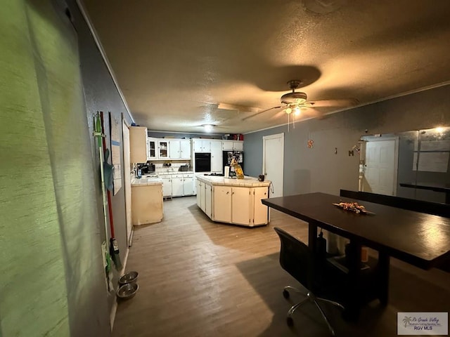 165 Johns Ave, Brownsville, TX 78521 - kitchen with black oven, a textured ceiling, white cabinetry, light wood-style flooring, and a ceiling fan