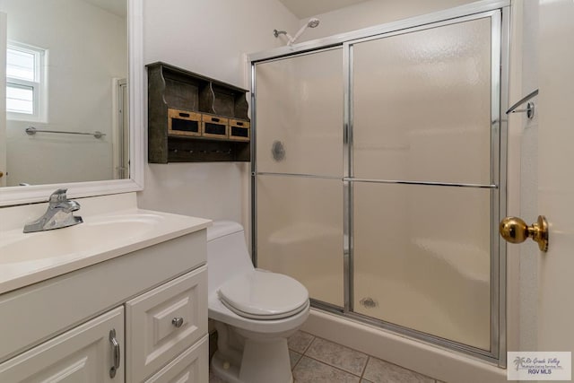 bathroom featuring tile patterned flooring, vanity, toilet, and a shower with door