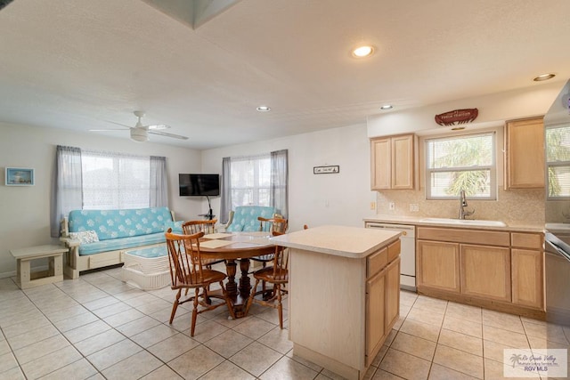 kitchen featuring dishwasher, sink, ceiling fan, light tile patterned floors, and a kitchen island