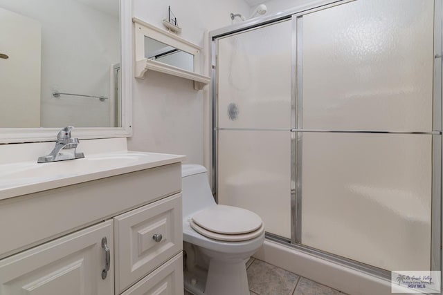 bathroom featuring tile patterned flooring, vanity, toilet, and a shower with shower door