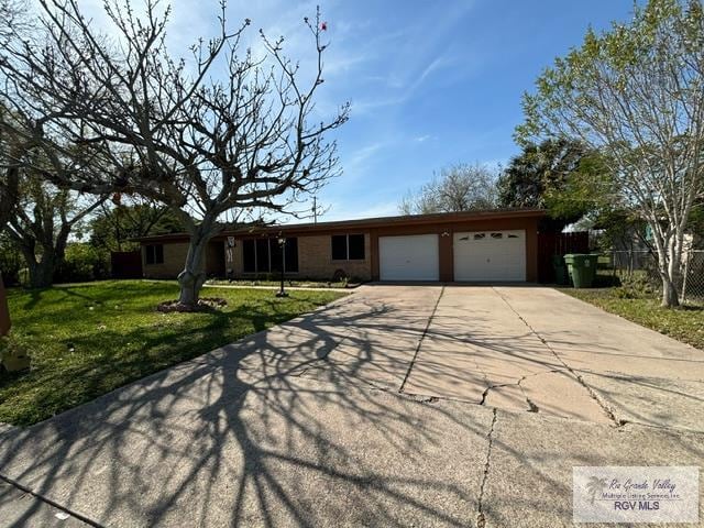 ranch-style home with a front lawn, fence, a garage, and driveway