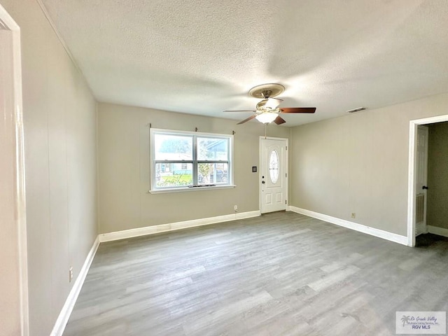 interior space featuring ceiling fan, a textured ceiling, and light hardwood / wood-style flooring