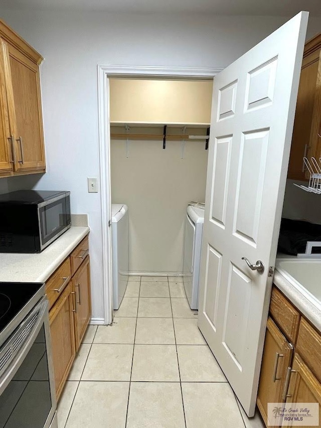 washroom with independent washer and dryer and light tile patterned floors