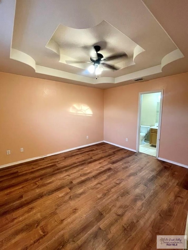 spare room with hardwood / wood-style flooring, ceiling fan, and a raised ceiling