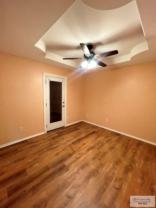 spare room featuring a raised ceiling, ceiling fan, and hardwood / wood-style floors