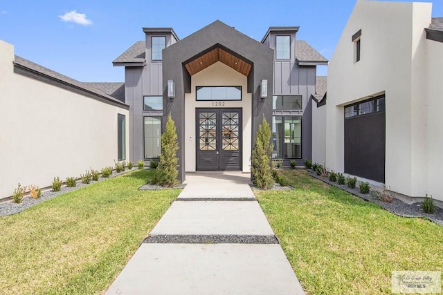 entrance to property with board and batten siding, stucco siding, a shingled roof, and a lawn