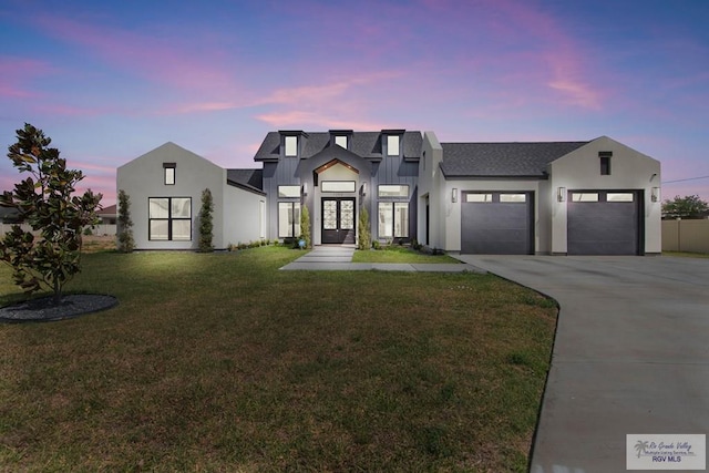modern inspired farmhouse with driveway, a garage, a lawn, and roof with shingles