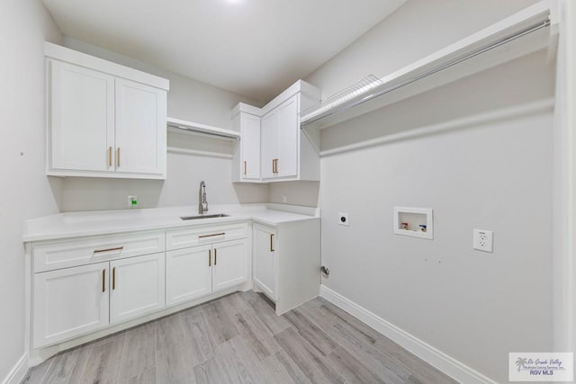 laundry area with hookup for a washing machine, a sink, light wood finished floors, cabinet space, and electric dryer hookup
