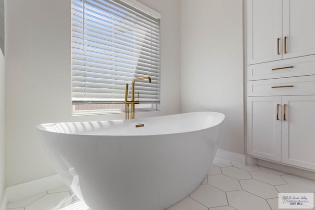 bathroom featuring baseboards, tile patterned flooring, and a freestanding bath