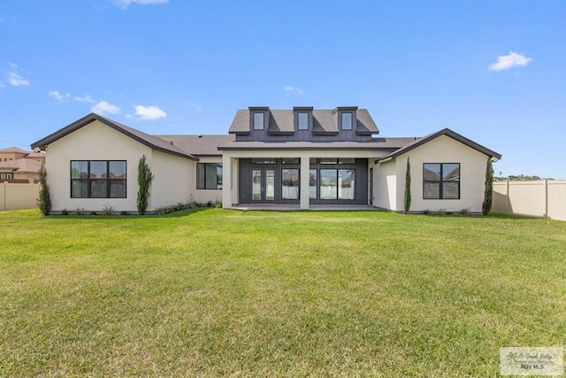 back of property featuring stucco siding, fence, and a lawn