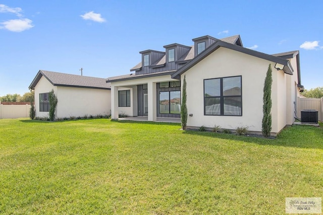 rear view of property featuring central AC unit, a lawn, stucco siding, and fence