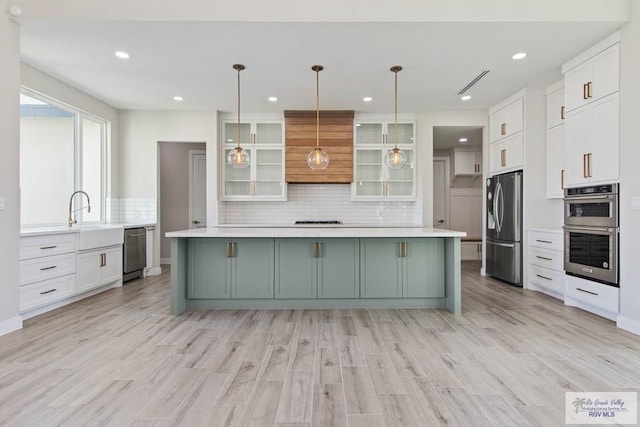 kitchen featuring white cabinetry, a sink, stainless steel appliances, and custom range hood