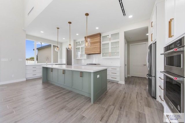 kitchen with white cabinetry, light countertops, decorative backsplash, a large island, and appliances with stainless steel finishes
