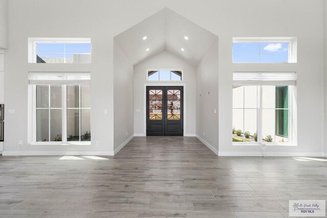 foyer entrance featuring recessed lighting, high vaulted ceiling, baseboards, and wood finished floors