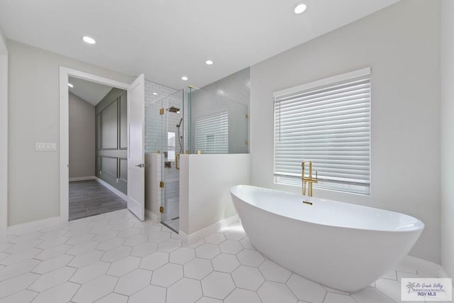 bathroom with baseboards, a stall shower, recessed lighting, and a freestanding bath