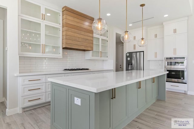 kitchen with white cabinetry, decorative backsplash, a large island, appliances with stainless steel finishes, and wood tiled floor