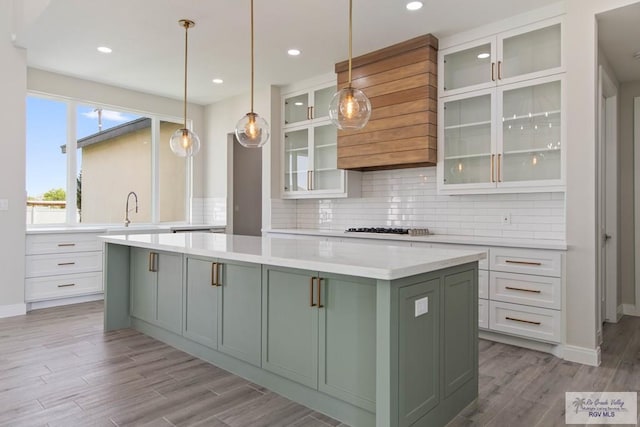 kitchen with decorative backsplash, white cabinetry, a kitchen island, and light wood finished floors