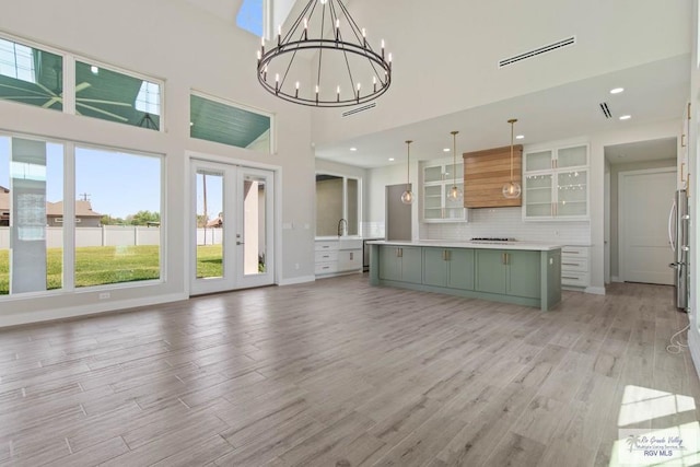 kitchen featuring light countertops, a center island, light wood-type flooring, visible vents, and decorative backsplash
