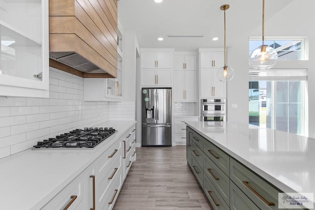 kitchen featuring light countertops, custom exhaust hood, and appliances with stainless steel finishes