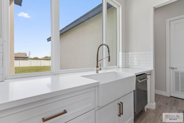 interior space featuring white cabinets, visible vents, light wood finished floors, tasteful backsplash, and a sink