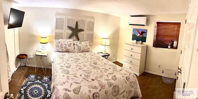 bedroom featuring an AC wall unit, dark tile patterned floors, and baseboards