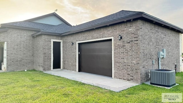 exterior space featuring central air condition unit, a yard, and a garage