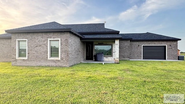 rear view of property featuring a garage and a lawn