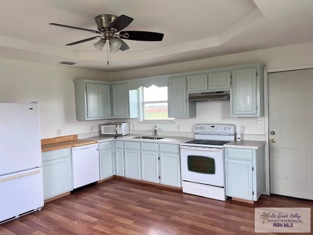 1056 E Mile 11, Weslaco, TX 78599 - kitchen with white appliances, under cabinet range hood, light countertops, a raised ceiling, and dark wood-style floors