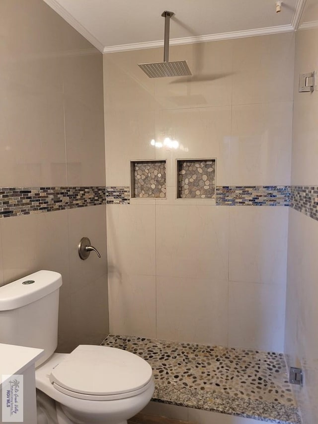 full bathroom with tiled shower, crown molding, vanity, and toilet