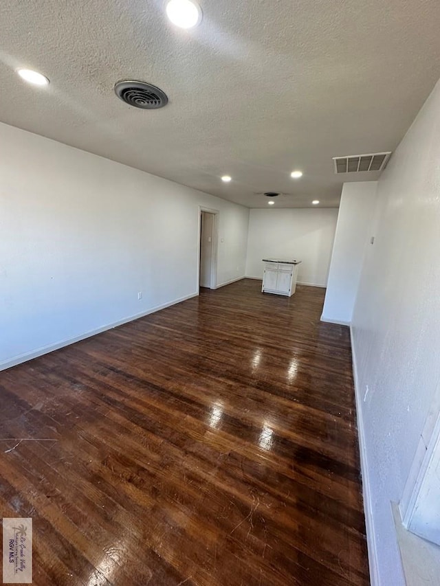 unfurnished room featuring a textured ceiling and dark hardwood / wood-style flooring