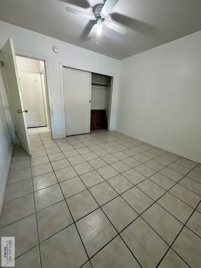 unfurnished bedroom featuring light tile patterned floors, a closet, and ceiling fan