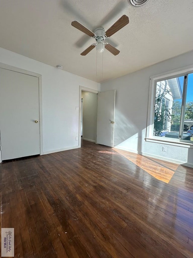 empty room featuring a textured ceiling, dark hardwood / wood-style floors, and ceiling fan