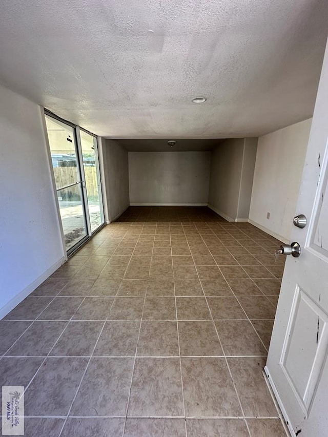 tiled empty room with a textured ceiling